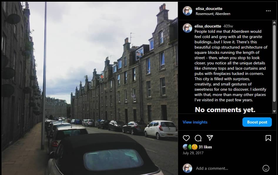 Screenshot of an Instagram post showing a photo of a narrow street in Aberdeen, Scotland, lined with tall granite tenement buildings under a cloudy sky. Cars are parked along both curbs, and the buildings stretch into the distance in clean, repetitive rows. Though stark at first glance, closer inspection reveals chimney stacks, lace curtains, and subtle architectural details; quiet signs of life and personalization in a city built from stone.
