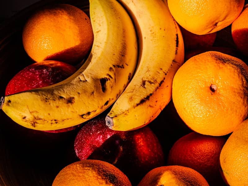 Bananas, oranges, and apples in a pile.