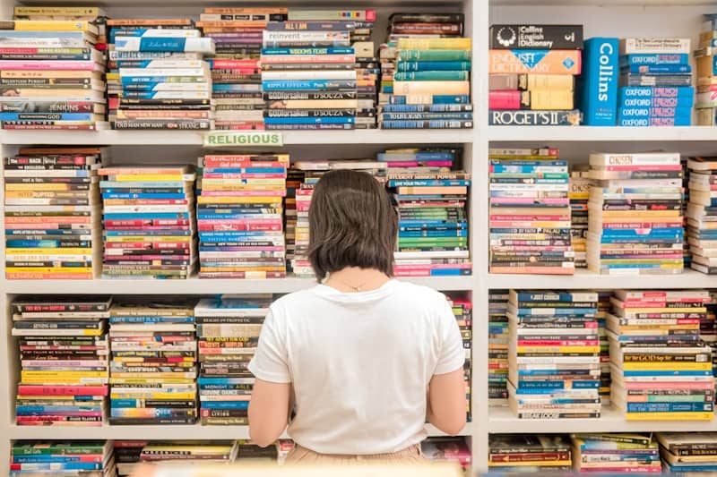 A person standing in front of a book shelf filled with books