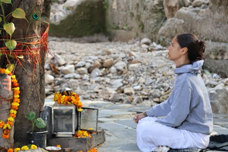 Woman meditating near a shrine with flowers.