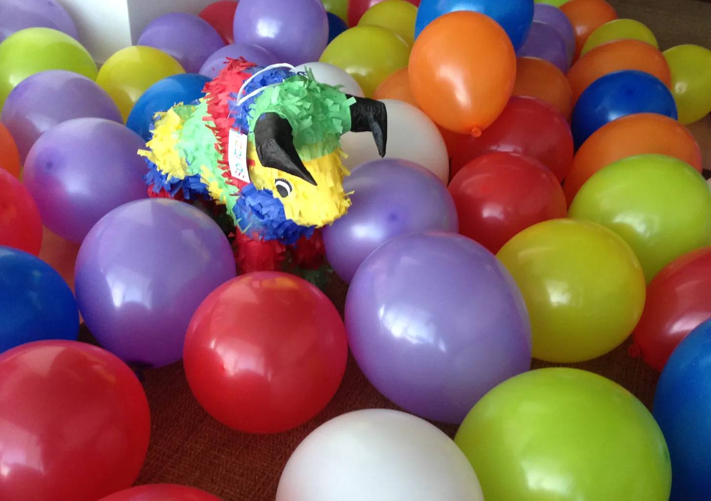 a pinata bull surrounded by dozens of colored balloons