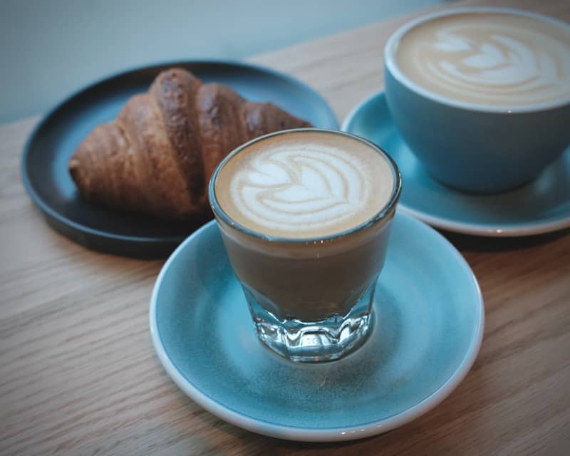 Two coffees and a croissant on a table