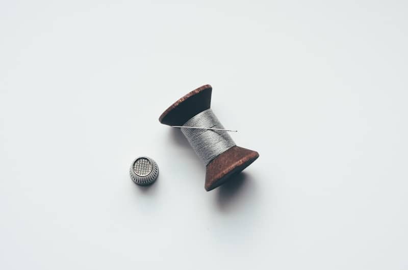 Spool of thread with a needle and thimble.