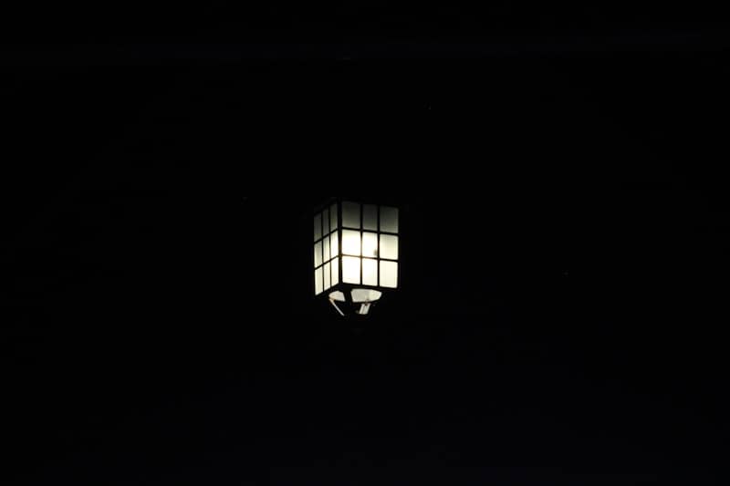 A lit lantern glows against a black background.