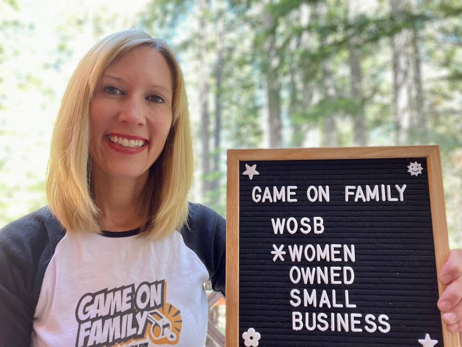 Picture of Game On Family founder with sign that says Game On Family Women Owned Small Business