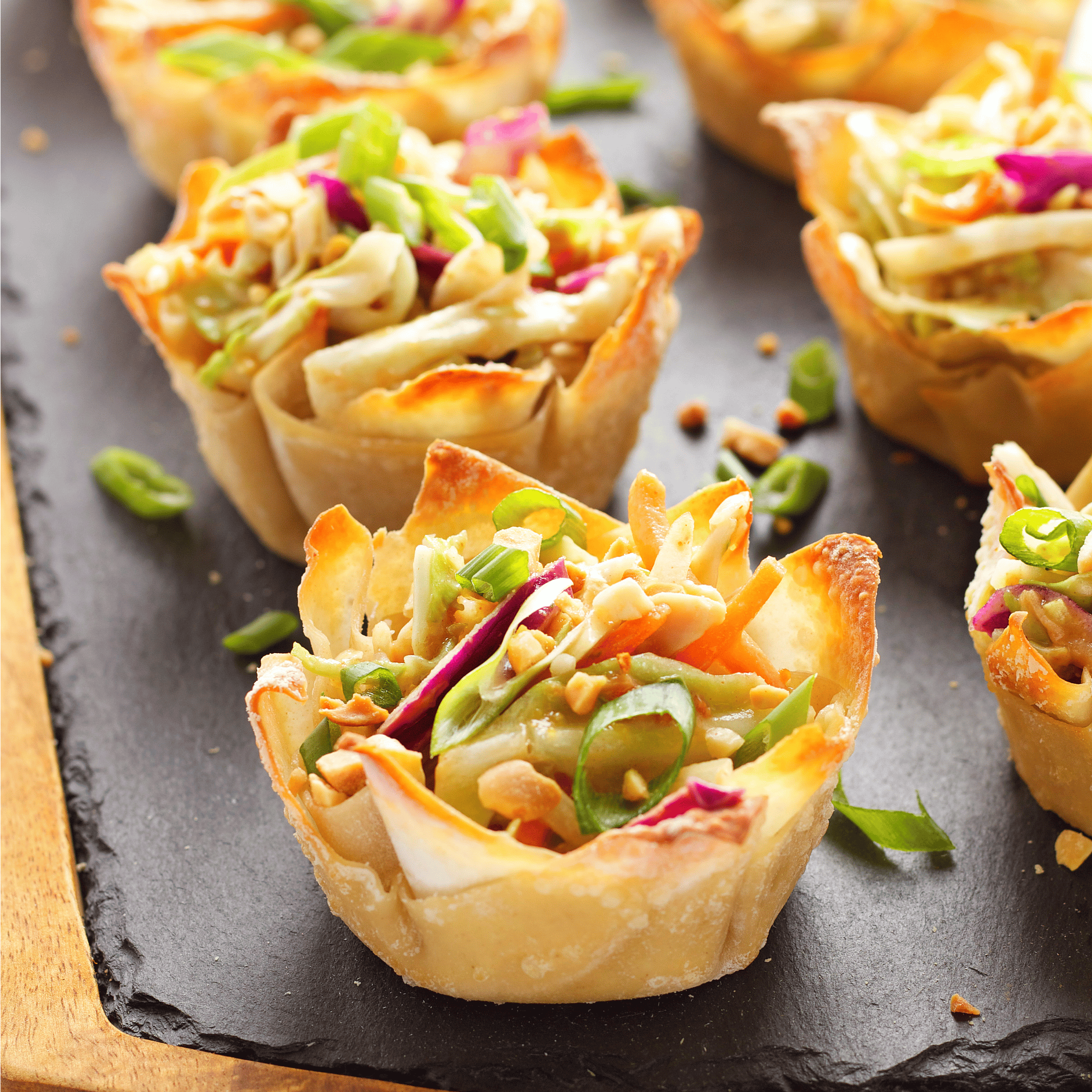 thai peanut salad in wonton cups on a slate board