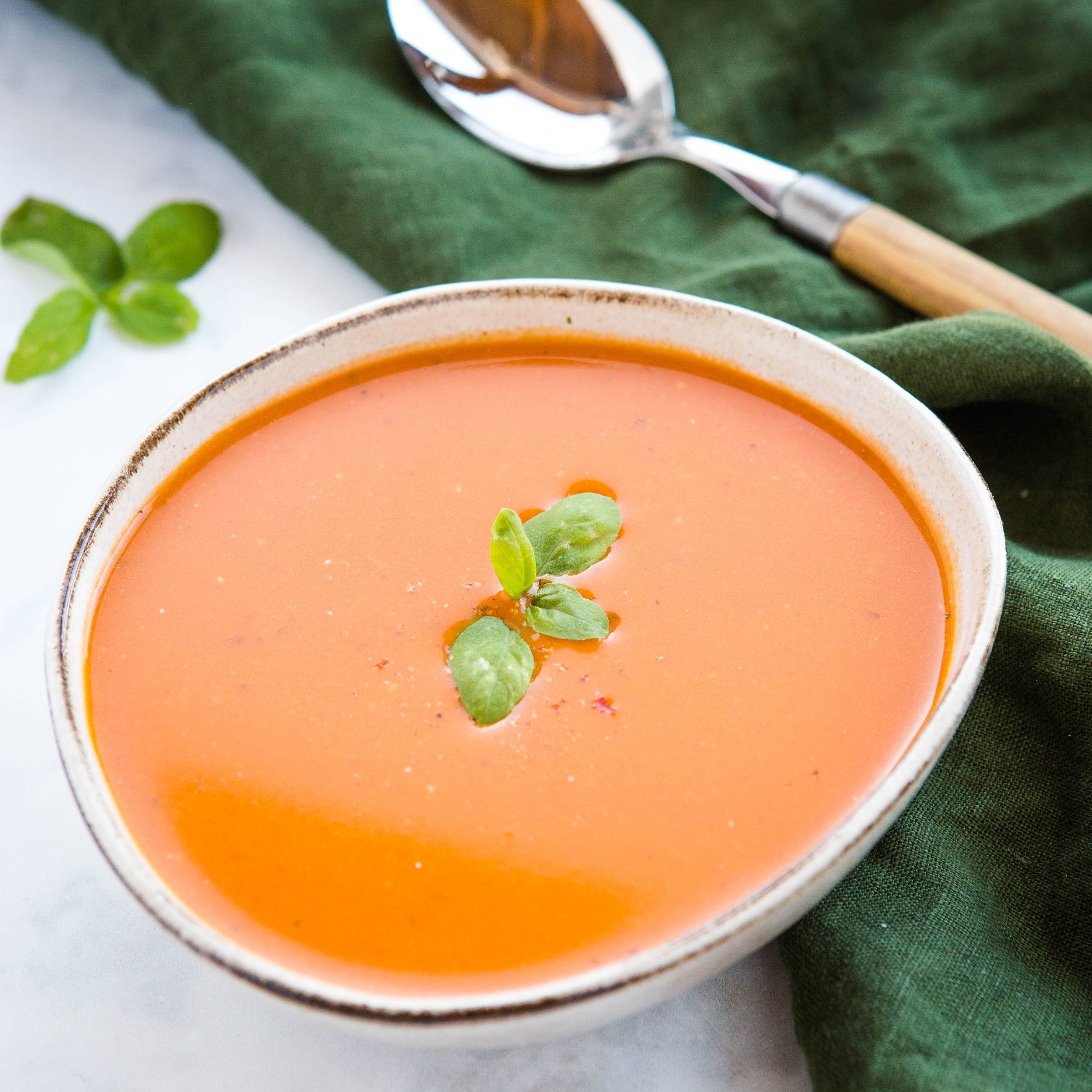 bowl of homemade tomato soup, topped with fresh basil