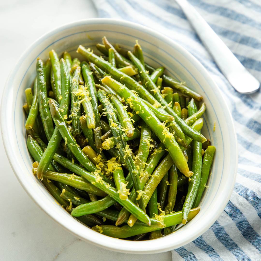 green beans in a serving dish topped with lemon zest