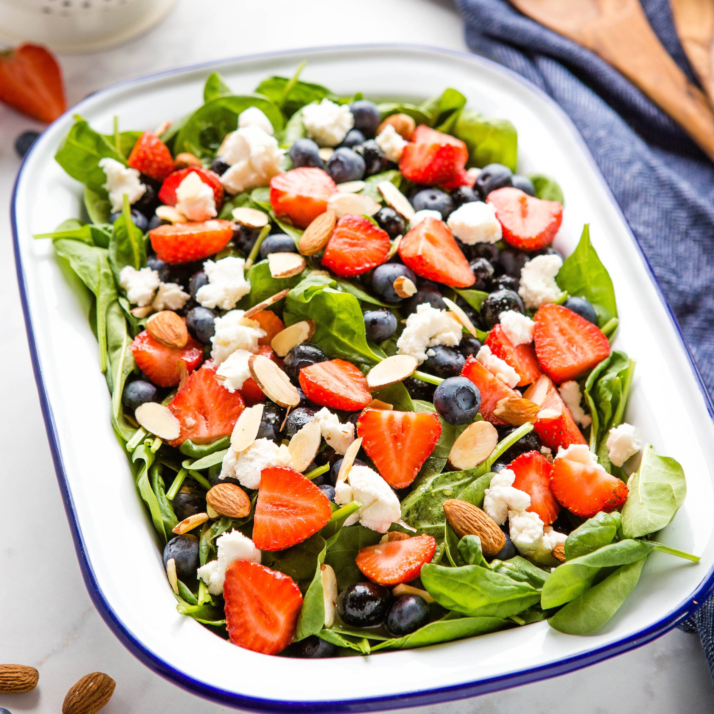 strawberries, blueberries, goat cheese, and slivered almonds on a bed of spinach