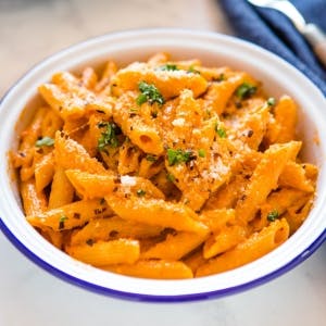 bowl of penne alla vodka garnished with fresh herbs