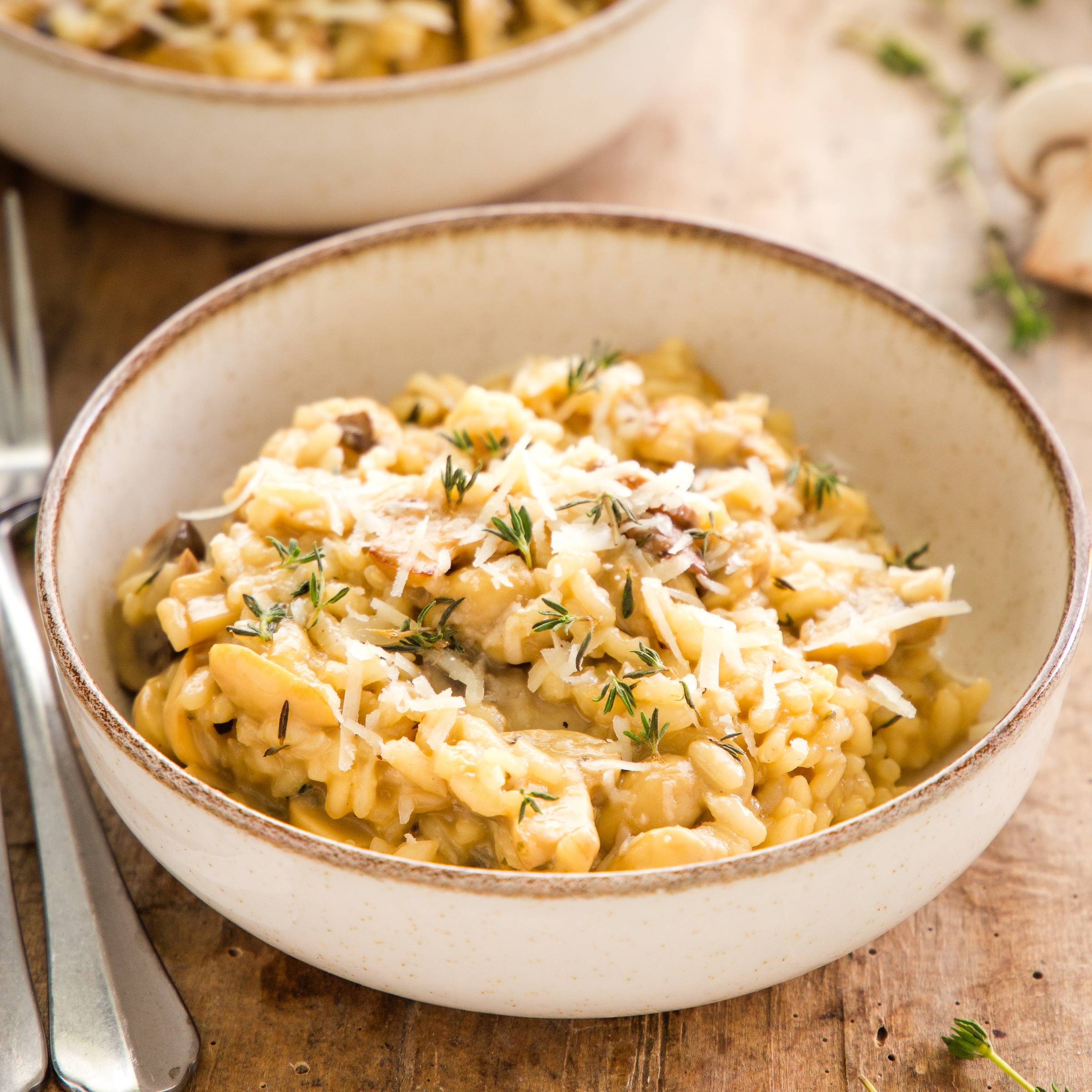 bowl of mushroom risotto topped with fresh Parmesan cheese and herbs
