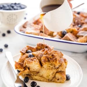 slice of French Toast Casserole on a plate being drizzled with syrup