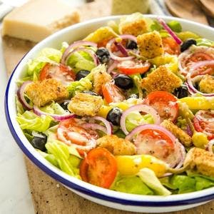 greens topped with sliced onions, tomatoes, peppers, black olives, an croutons