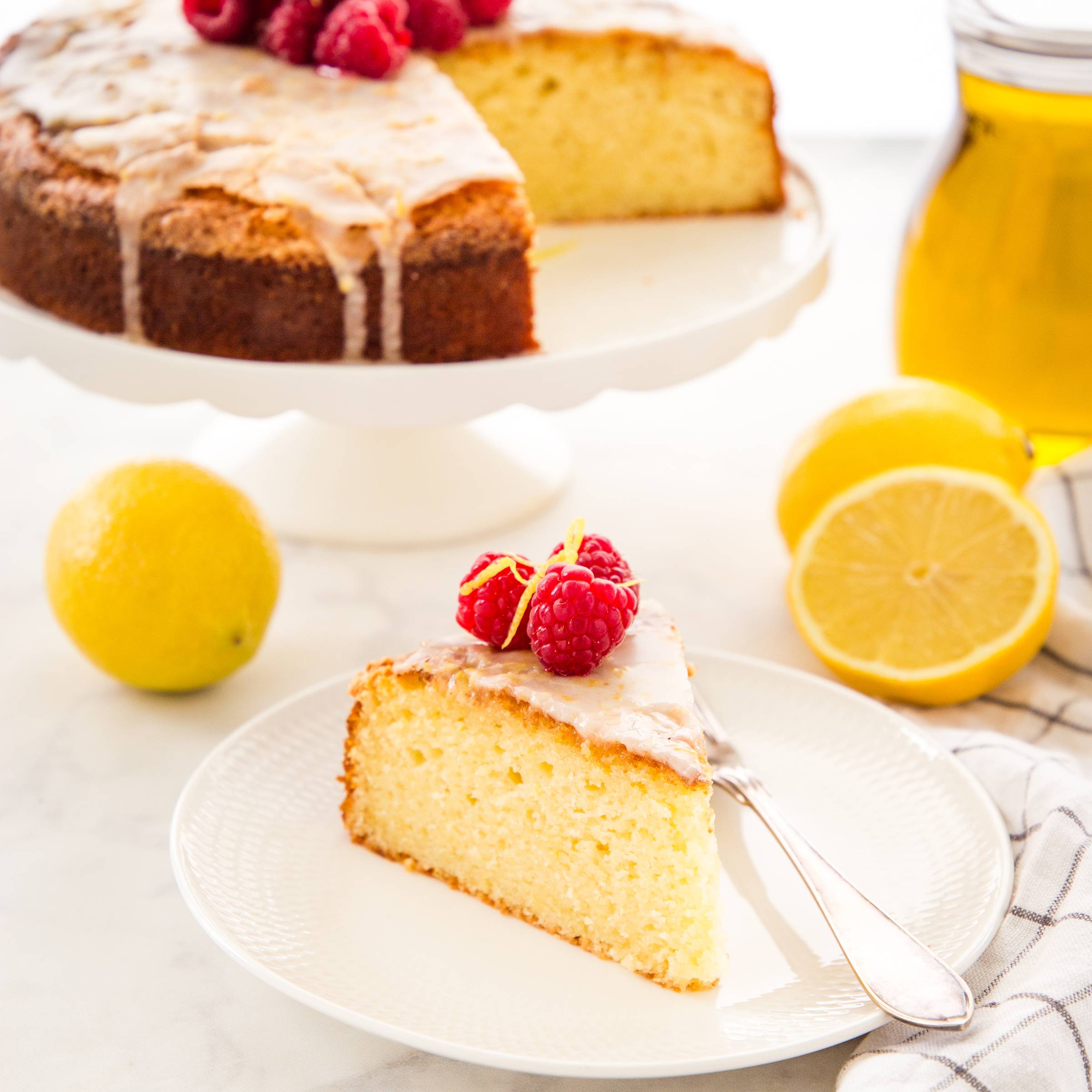 slice of olive oil cake topped with glaze and raspberries