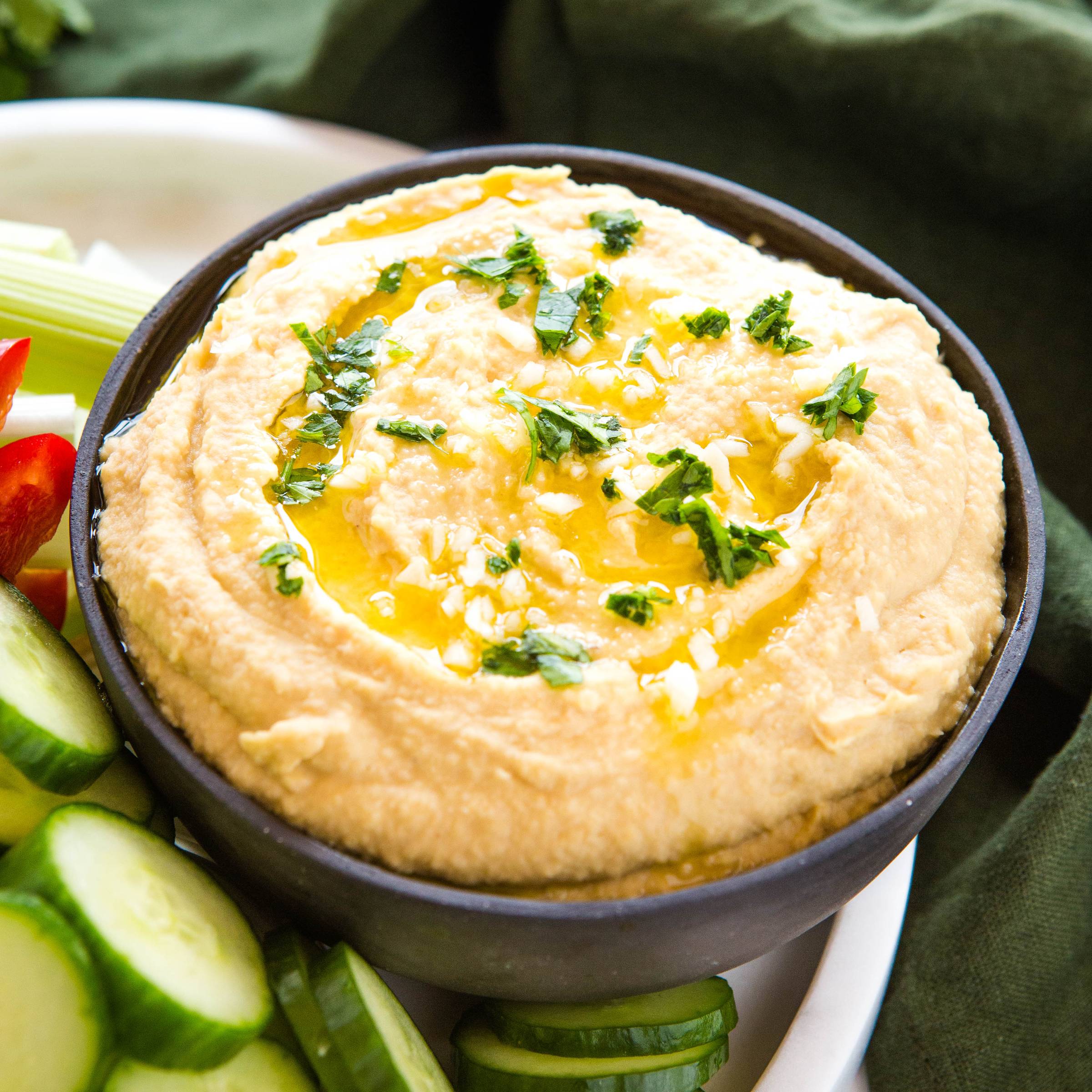 bowl of hummus drizzled with olive oil and topped with chopped herbs