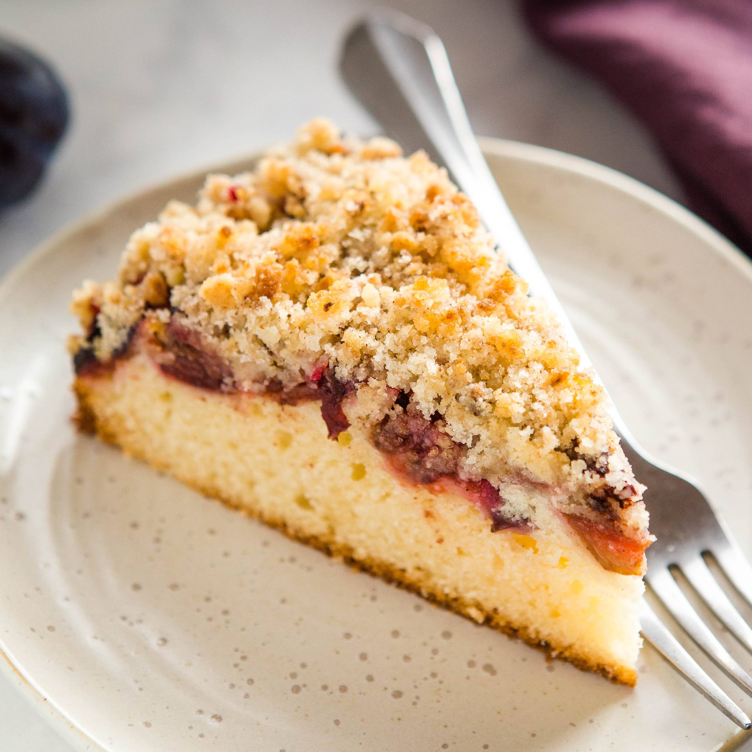 a slice of yogurt plum cake with crumb top on a plate