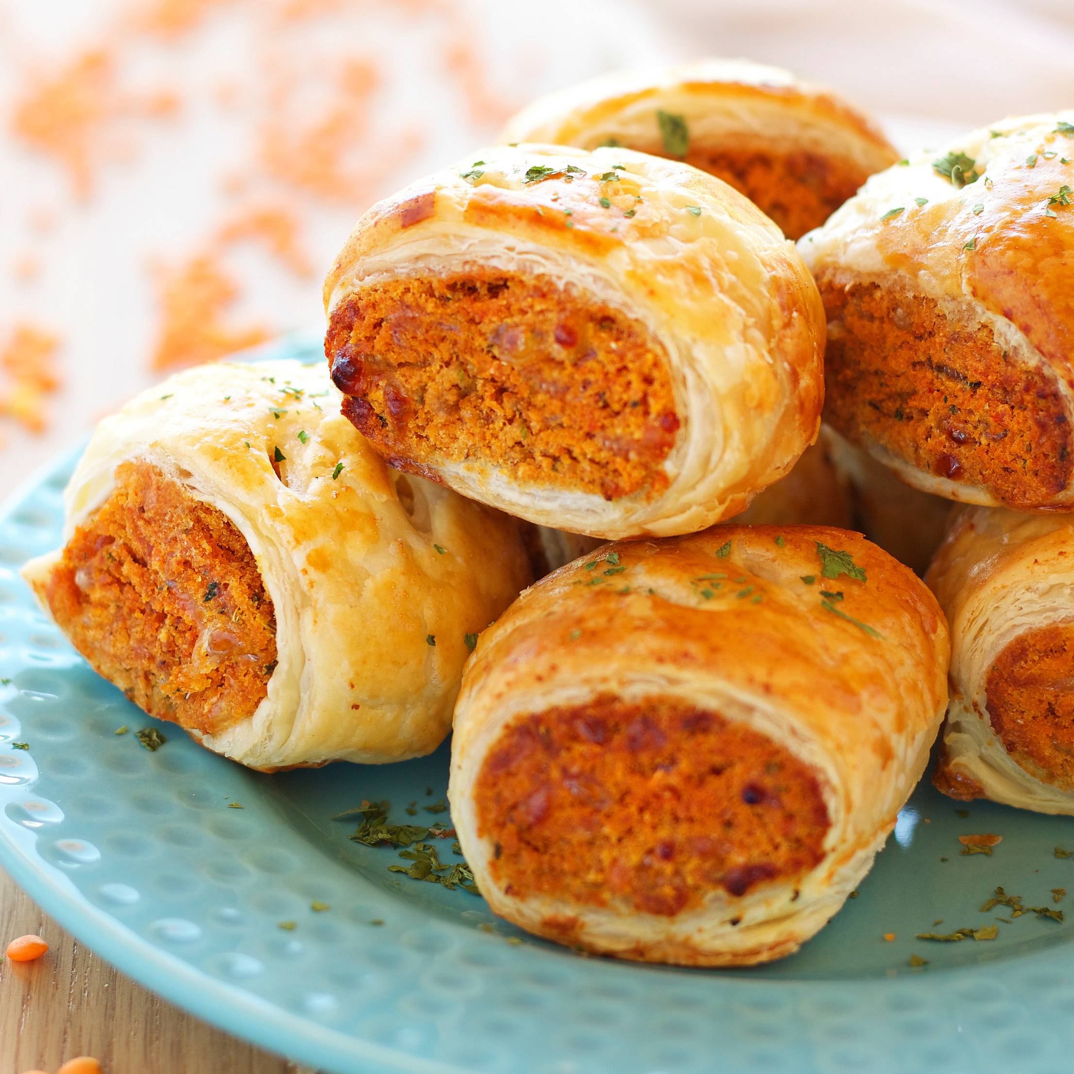 red lentil sausage rolls stacked on a plate
