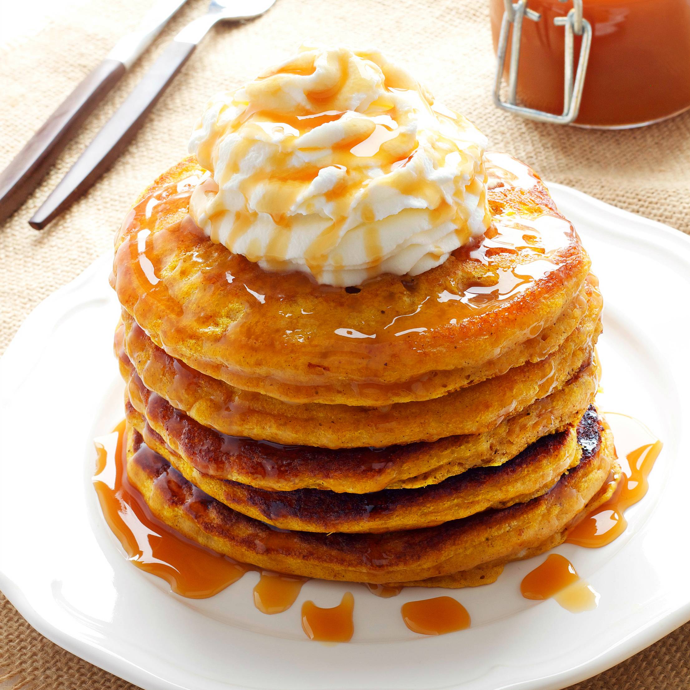 a stack of pumpkin pancakes with whipped cream on top