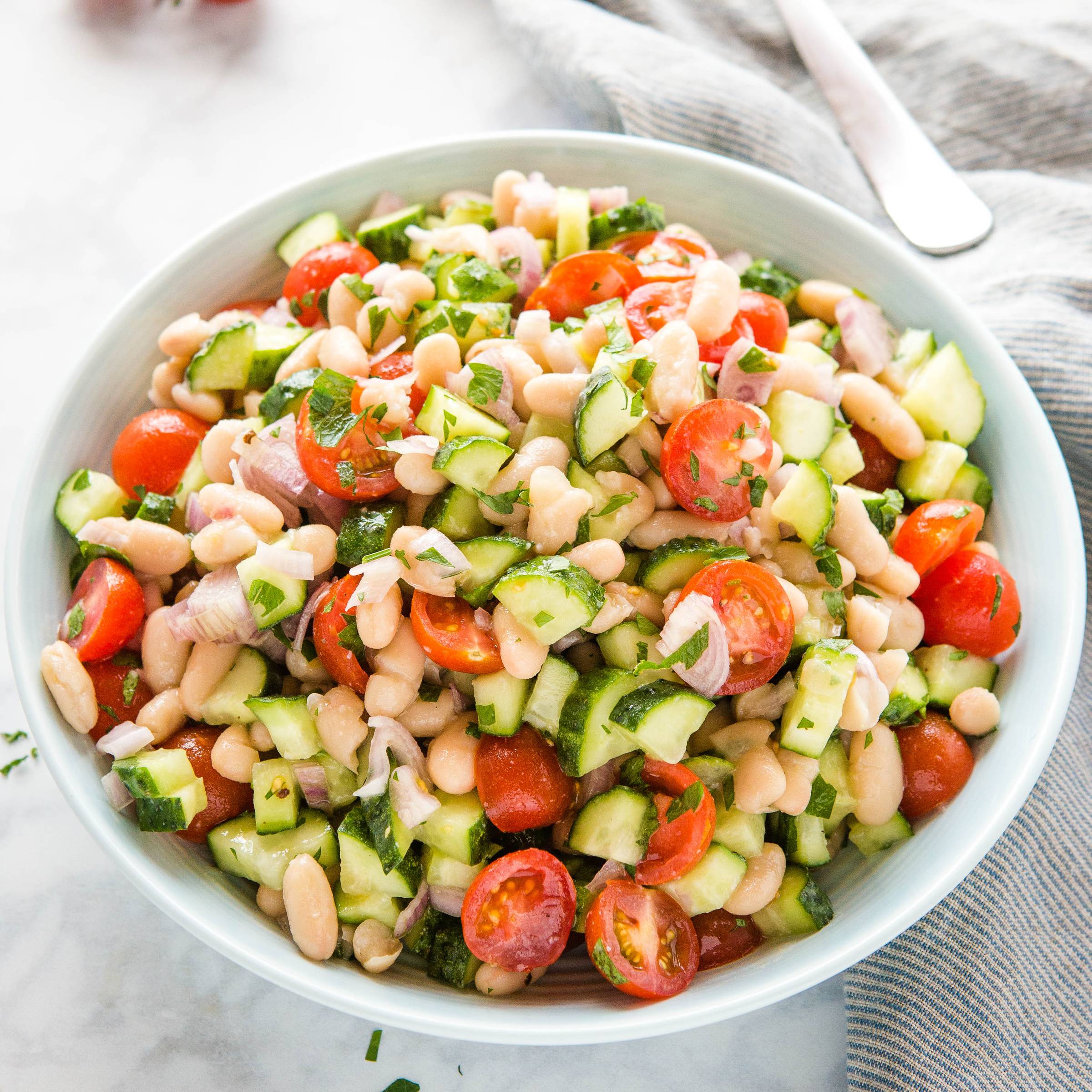 white bean salad with tomatoes and cucumbers in serving bowl