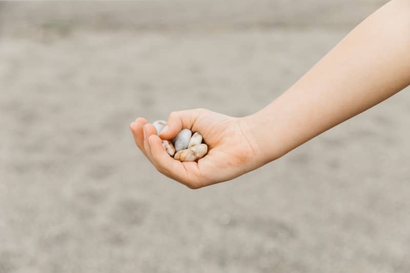 A child holds small, smooth stones in their hand.
