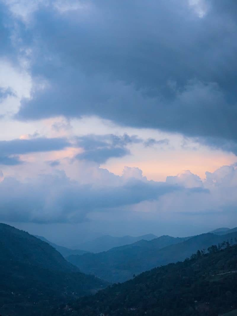 Dramatic clouds hover over majestic mountain peaks.