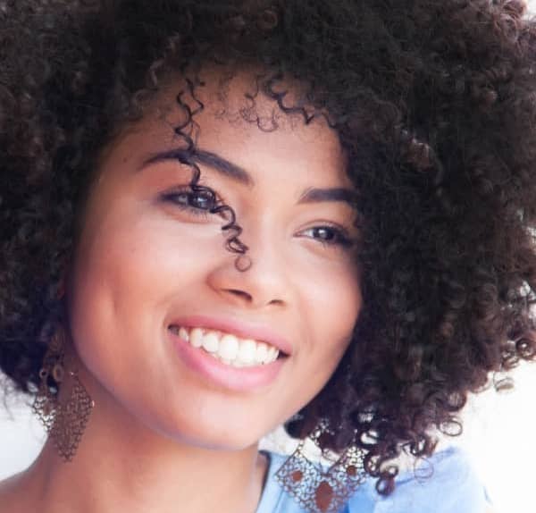African American woman with curly hair looking in the distance smiling.