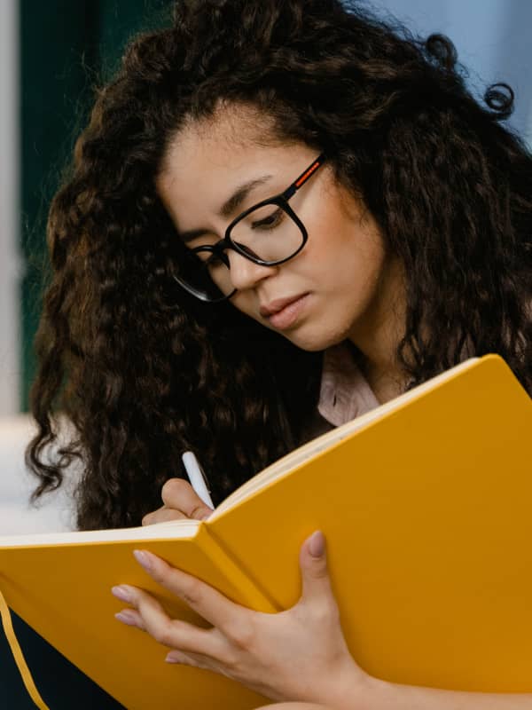 A mom writing in a yellow journal. 