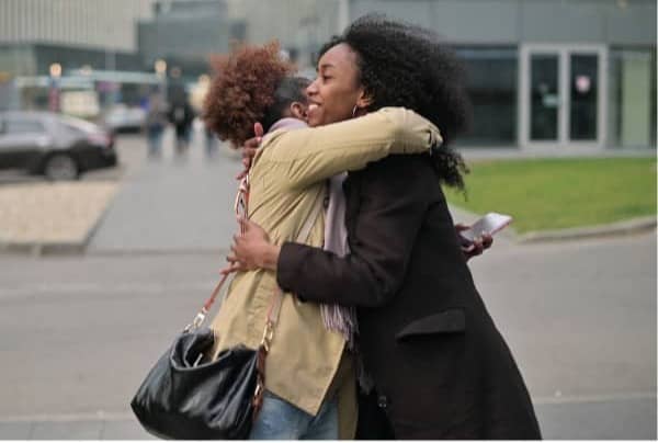 Two women hugging and smiling in a parking lot.