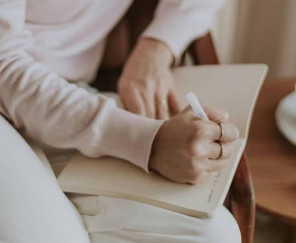 Picture of a woman sitting in a chair writing in her journal.