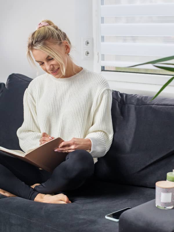 Mom sitting crisscrossed on couch, writing in her journal