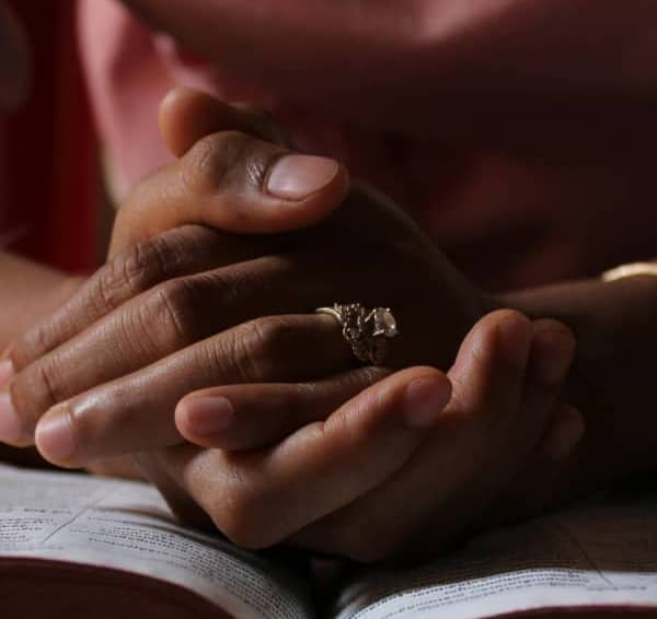 Woman's prayer hands on top of a bible.