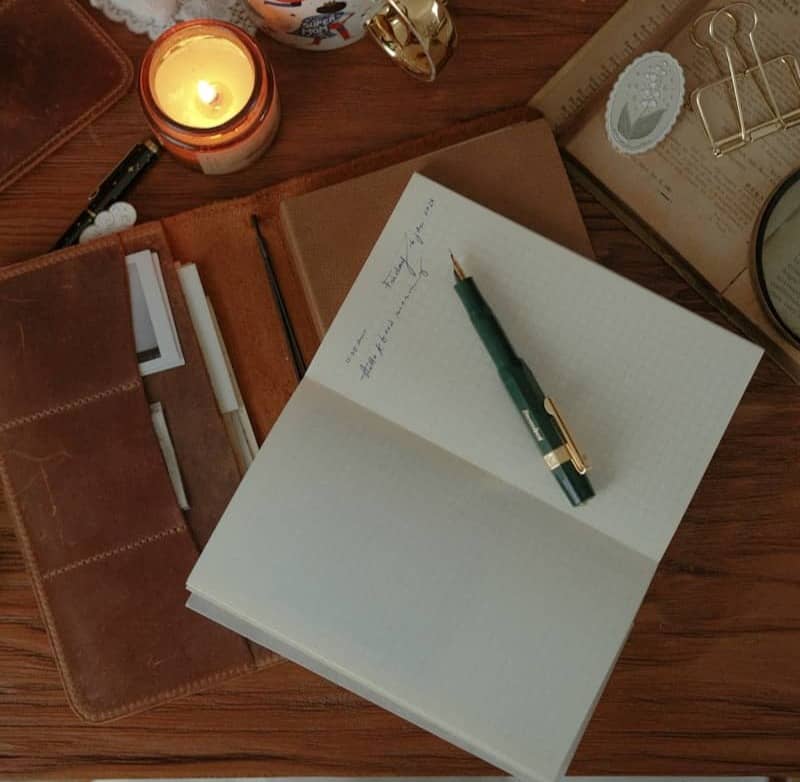 A cozy desk scene with a lit candle and coffee