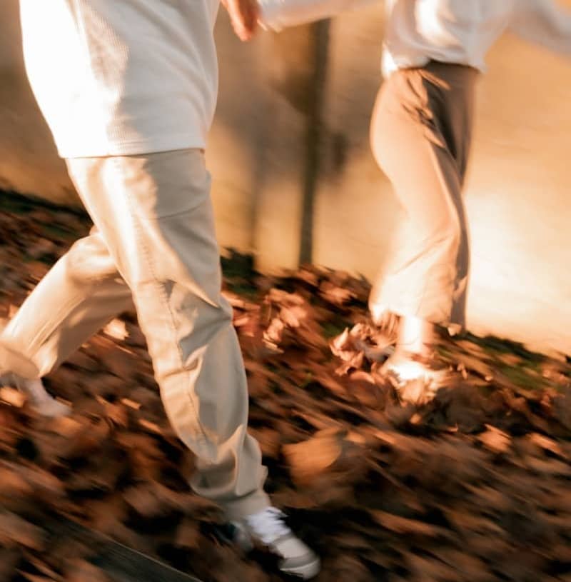 Two people walking through autumn leaves with motion blur.