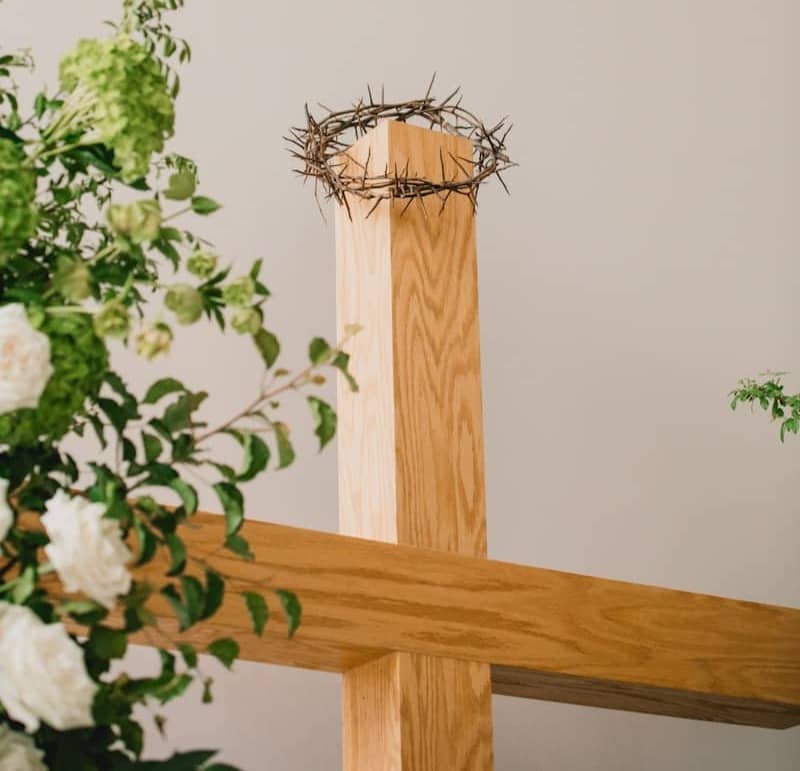 Crown of thorns on a wooden cross with flowers