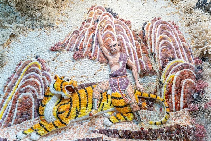 Man riding a tiger with mountains behind him.