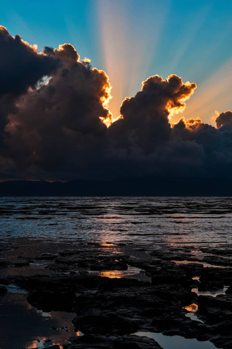 Sunbeams burst through dramatic clouds over ocean