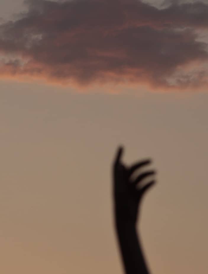 Silhouette of a hand reaching for a cloud