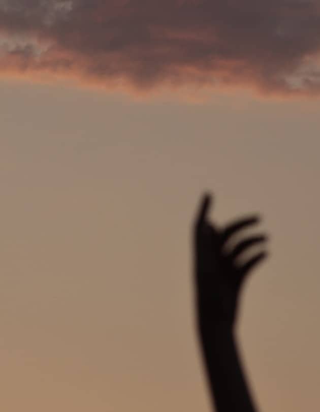 Silhouette of a hand reaching for a cloud