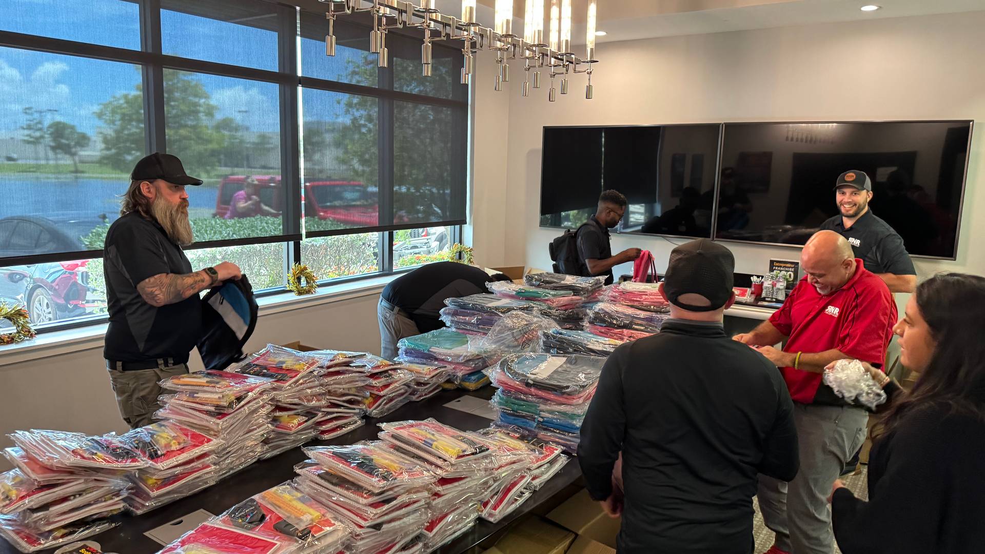 People arround a table stuffing backpacks with supplies