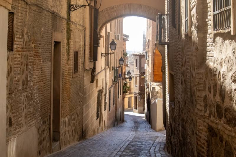 A narrow, old alleyway leads into the distance.