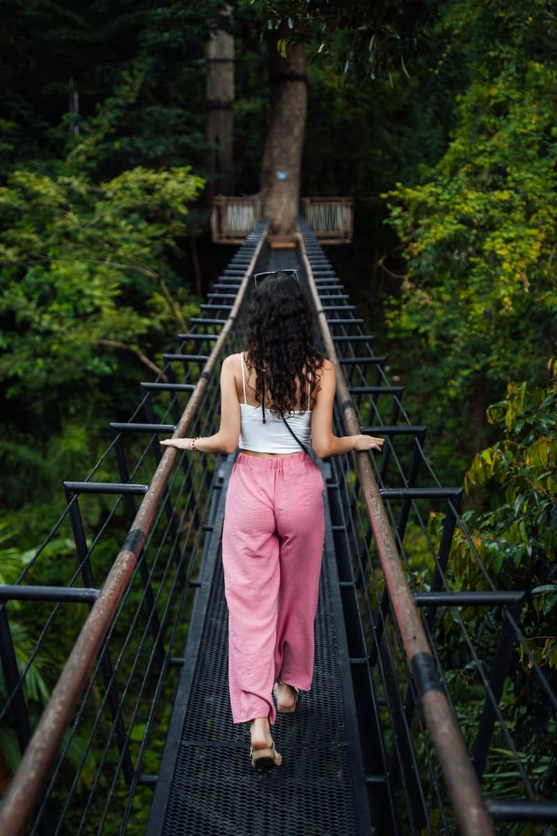 A woman walking across a suspension bridge in the jungle
