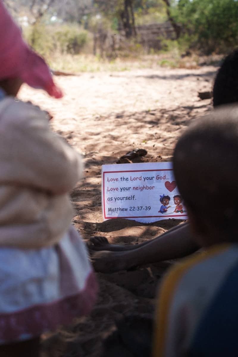 Children gathered around a sign with bible verse