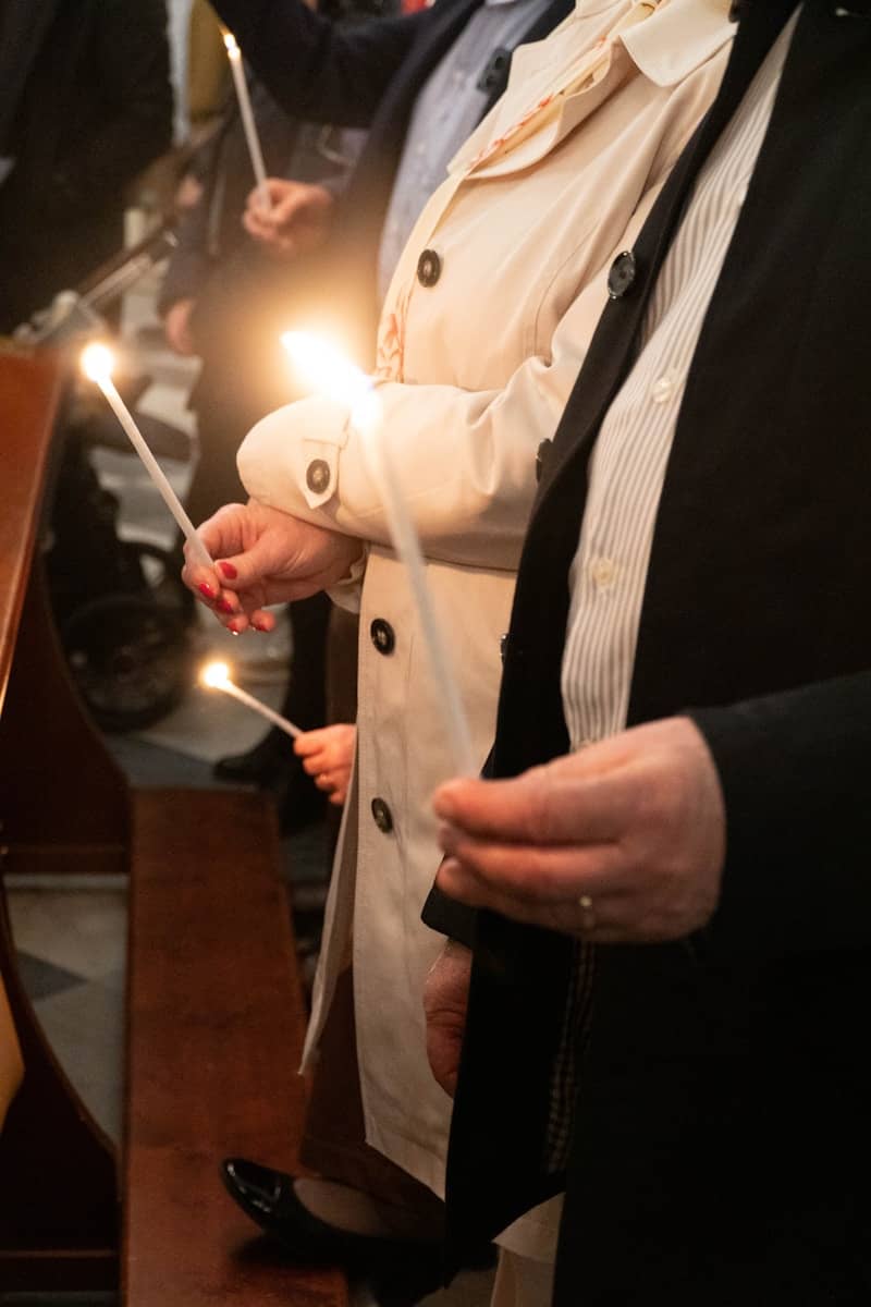 People are holding lit candles in a dimly lit place.