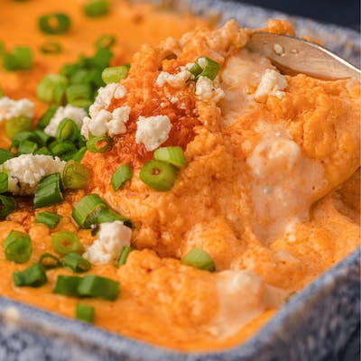 Frank's RedHot buffalo chicken dip topped with blue cheese crumbles and green onion topss
