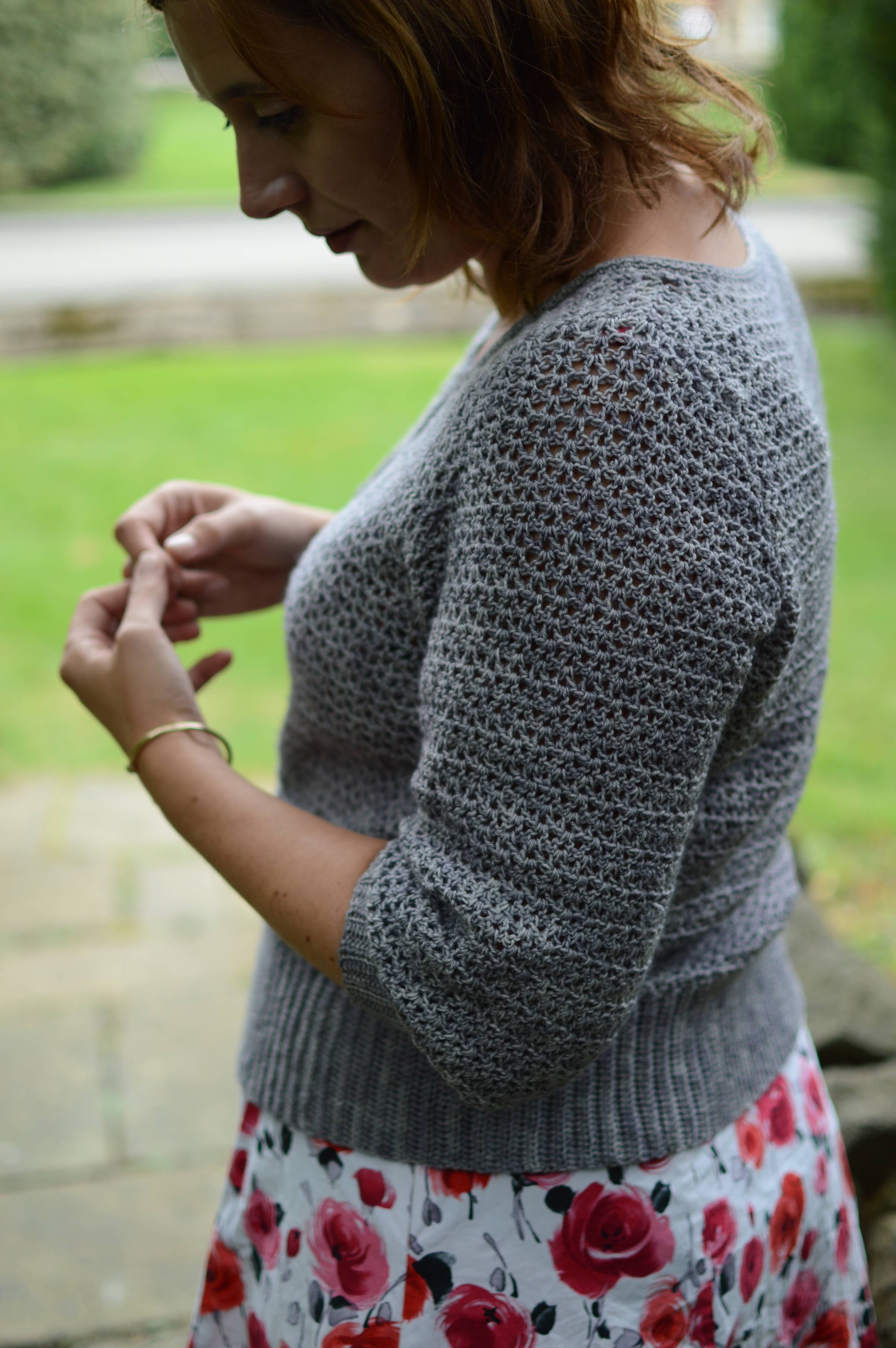 joanne wears a grey Alyssium cardigan, she is turned to the side with shoulder visible, indestinct background