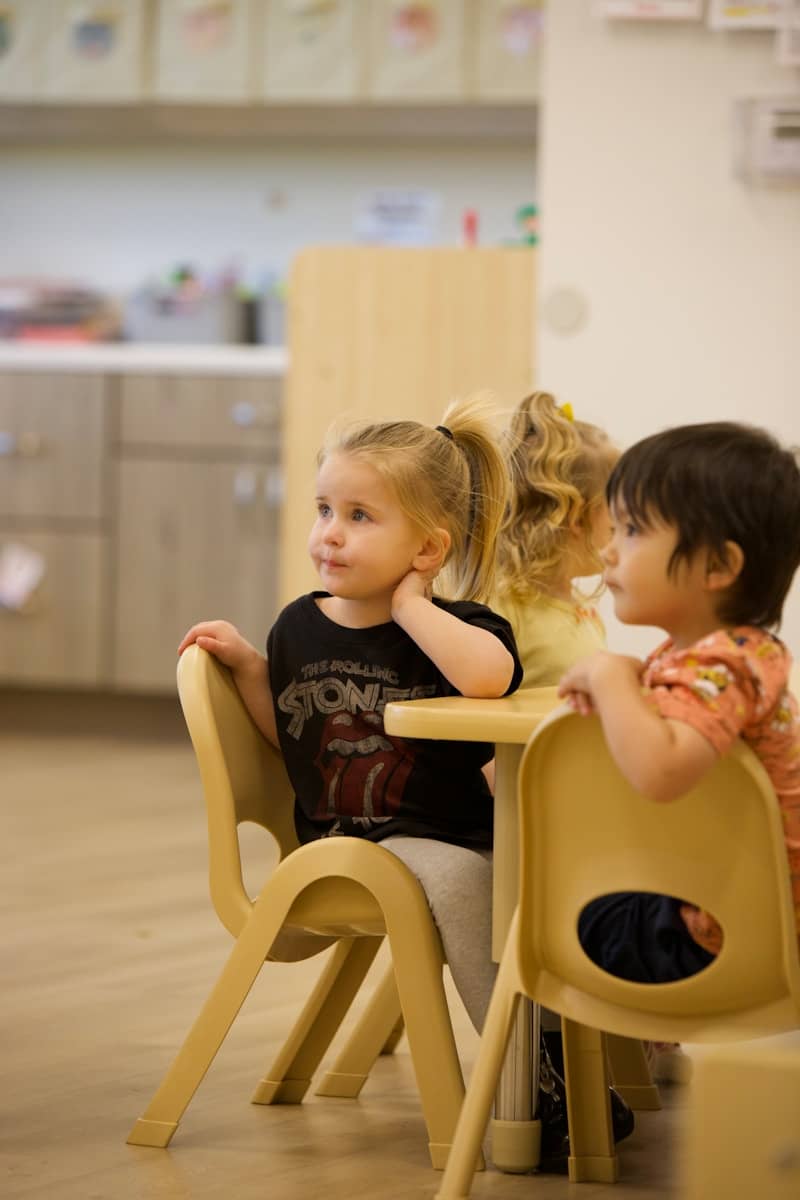 Young children sitting at a table in a classroom.