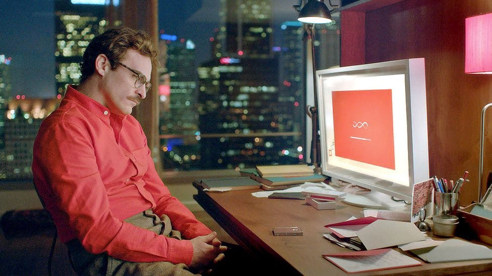 A still from the movie 'Her', showing Theodore Twombly at a desk in front of his computer