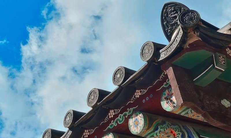 Colorful traditional korean roof against a blue sky.