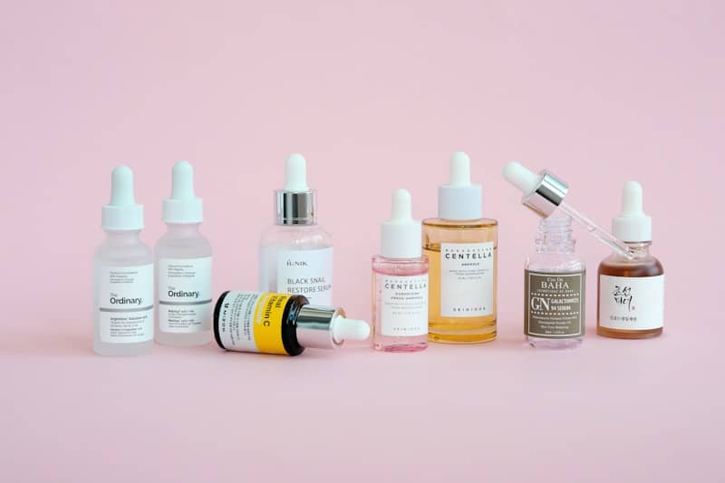 Skincare products are arranged on a pink background.