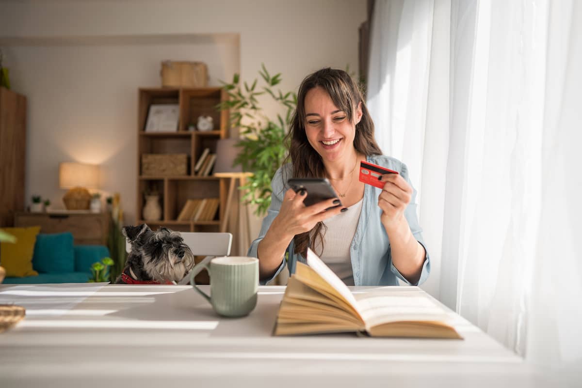Woman shopping online with a smartphone and credit card at home